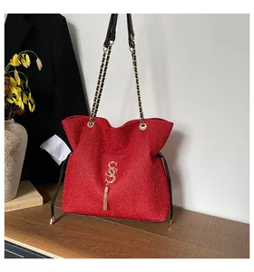 Detalle de bolso bandolera rojo brillante con logo SS dorado, flecos y cadena