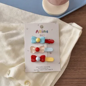 Close-up of three colorful resin bow hair clips on a card over a cozy knit texture