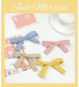 Detail of four fabric bow hair clips in pastel blue, pink, yellow, and beige for girls