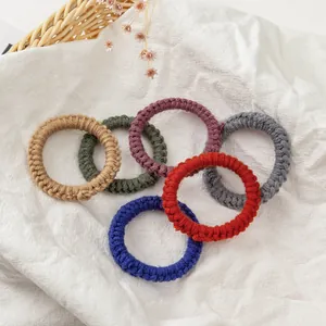 Lot de six élastiques à cheveux tricotés à la main en plusieurs couleurs sur lin blanc