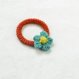 Détail d'un élastique à cheveux crocheté à la main avec motif floral bleu sur tricot orange