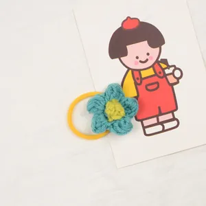 Detailed macro view of blue handmade crochet flower hair tie with yellow core and elastic band