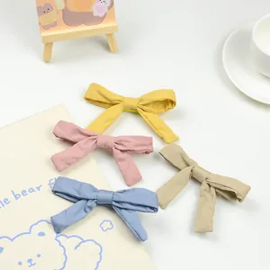 Set of four solid color fabric bow hair clips for girls in pastel yellow pink blue and beige