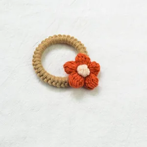 Détail du chouchou fait main au crochet avec petite fleur tricotée orange sur laine brune