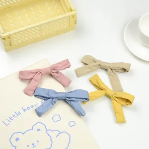 Detail view of 4-pack fabric bow hair clips in pastel colors for girls' hair styling