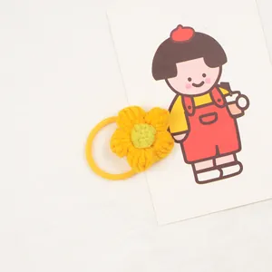 Close-up of a handmade yellow crochet flower hair tie for girls with green center