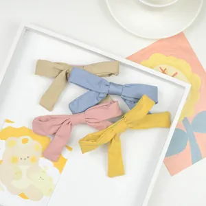 Set of 4 colorful linen fabric bow hair clips for girls in a stylish wooden tray