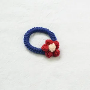 Détail d'un chouchou en tricot bleu foncé avec une fleur rouge faite à la main