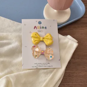 Detail of yellow polka dot and beige plaid bow hair clips on a branded display card