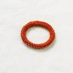 Détail de l'élastique à cheveux tricoté à la main avec texture crochet orange