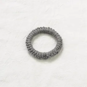 Vue macro d'un chouchou en maille grise avec texture spirale sur fond de lin