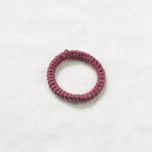 Détail d'un élastique à cheveux en laine tricotée à la main de couleur vieux rose