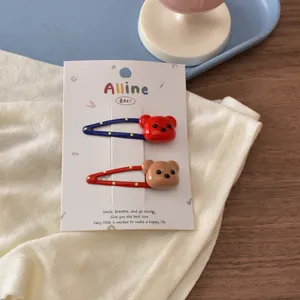 Detail showing two bear-shaped hair clips in blue and red on a white display card