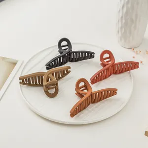 Close-up of four large matte hair claws in various colors arranged on a white ceramic plate
