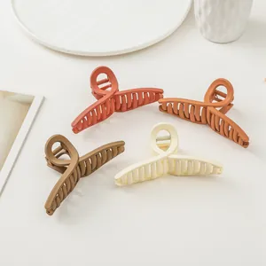 Matte hair claw clips in four earth tones arranged on a clean white aesthetic surface