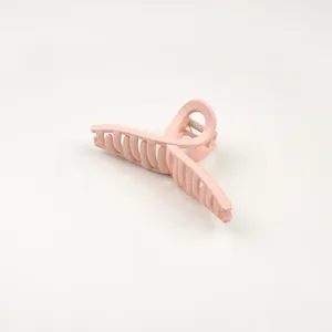 Detail of a large matte pink hair claw clip featuring a sturdy metal spring and firm teeth