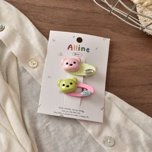 Detail of pink and green bear hair clips with handmade labels on display card