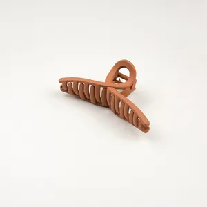 Close-up of a matte caramel hair claw clip with cross-teeth design on white background