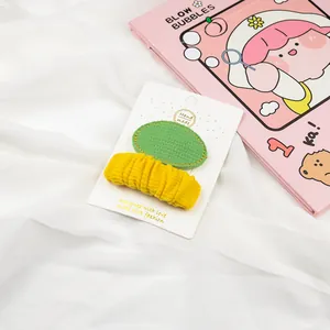 Detail of green oval and yellow pleated fabric hair clips for girls on a handmade card