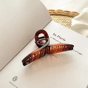 Détail d'une grande pince à cheveux écaillée posée sur un livre au style français chic