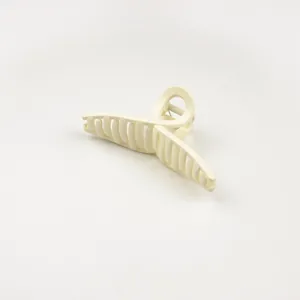 Detail showing creamy matte hair claw clip with cross design and metal spring mechanism