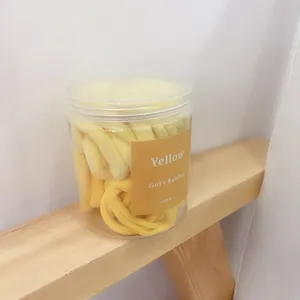 Detailed macro shot of yellow seamless elastic hair ties in a clear cylindrical jar