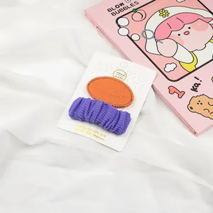 Detail of orange and purple fabric hair clips for girls on a white display card