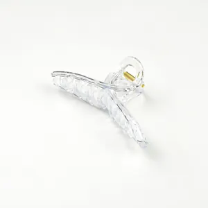 Detail view of a clear acrylic cross hair claw clip with a durable gold metal spring