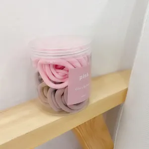 Pastel pink and brown elastic hair ties stored in a round jar with a pink label