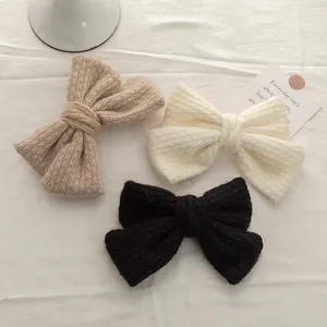 Three knit bow hair clips in black, beige, and cream made of soft mohair knit yarn