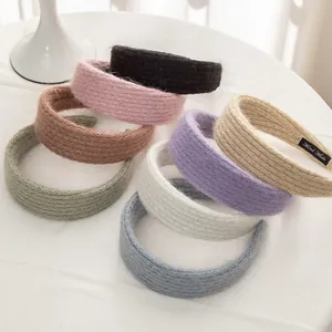 Detail of colorful knitted mohair headbands with a handmade label on soft fabric