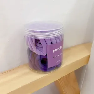Detail of purple seamless high elasticity hair ties in a clear cylindrical storage jar