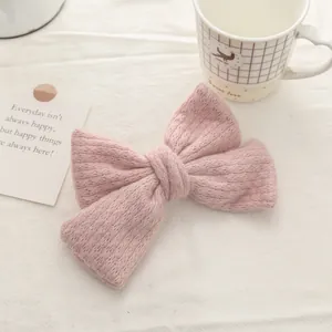 Detail of pink knitted double bow hair clip on a soft white linen background