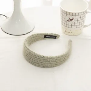 Close-up of light green knit headband featuring a white Handmade label on the inner side