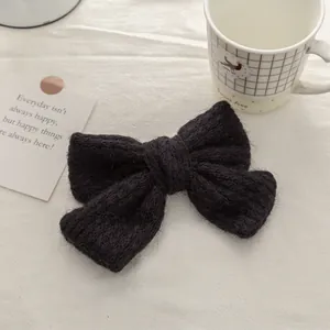 Close-up of black knitted mohair double bow hair clip with textured wool fiber detail