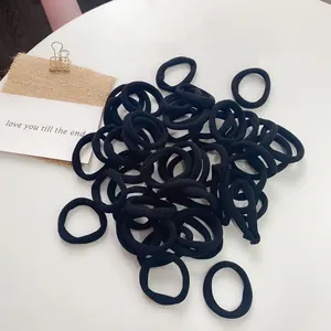Close-up of black seamless hair ties with high elasticity stacked on a rustic backdrop