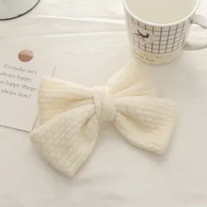 Close-up of cream white knitted double bow hair clip with soft mohair texture