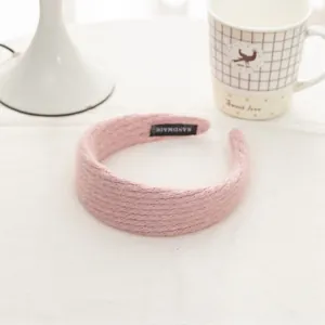 Detail of pink knitted headband with handmade label on soft wool texture