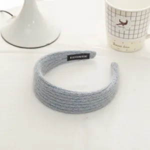 Detail of light blue chunky knit headband with a black handmade label on soft fabric