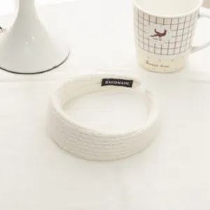Close-up of white knitted headband with handmade label and ribbed texture