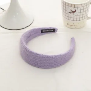 Detail of light purple mohair knit headband with a black handmade label on soft fabric
