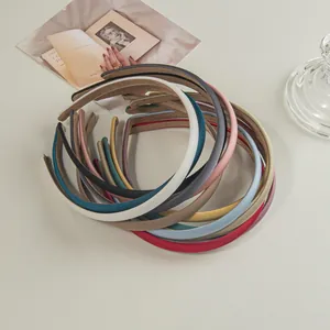 Detailed top view of various colored satin headbands stacked on a minimalist desk