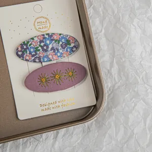 Détail de broderie florale sur pinces à cheveux en tissu bleu et violet sur support