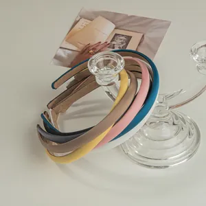 Multi-colored satin thin headbands stacked on a glass stand with an artistic background