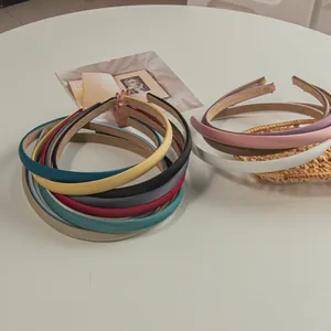Detail showing various solid colors of sleek minimalist slim headbands on a table