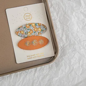Gros plan de barrettes à fleurs brodées à la main sur une carte de présentation