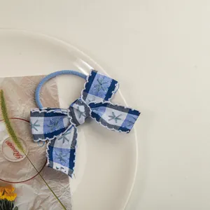 Gros plan d'un chouchou à nœud vichy bleu avec broderie sur une assiette en céramique