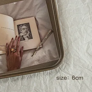 Dettaglio di un fermaglio dorato da 6cm con strass scintillanti su un libro vintage