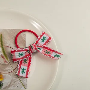 Détail d'un chouchou à nœud rouge à carreaux avec broderie et dentelle sur assiette blanche