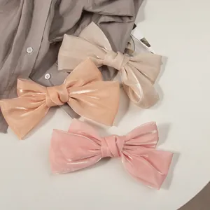 Détails de pinces à cheveux en satin irisé aux tons beige, orange et rose poudré
